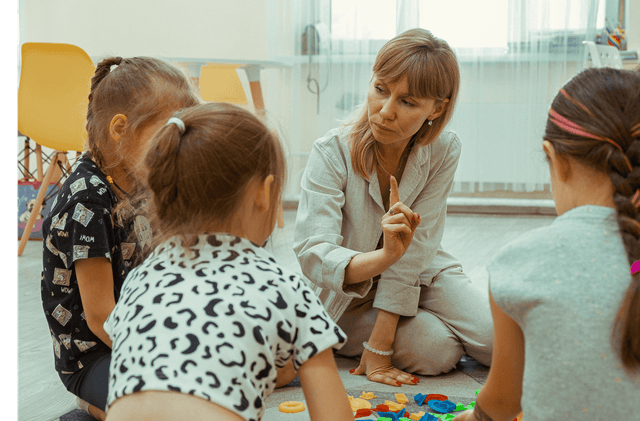 Учитель играет с двумя маленькими детьми.